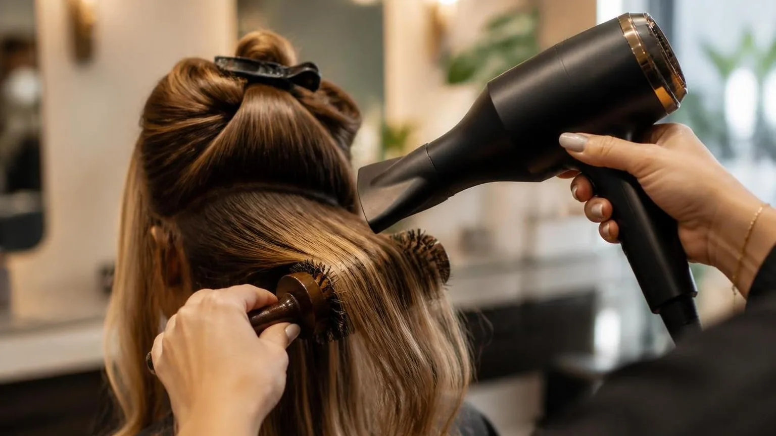 A stylist working through a sectioned blow dry, close-up, in a working salon