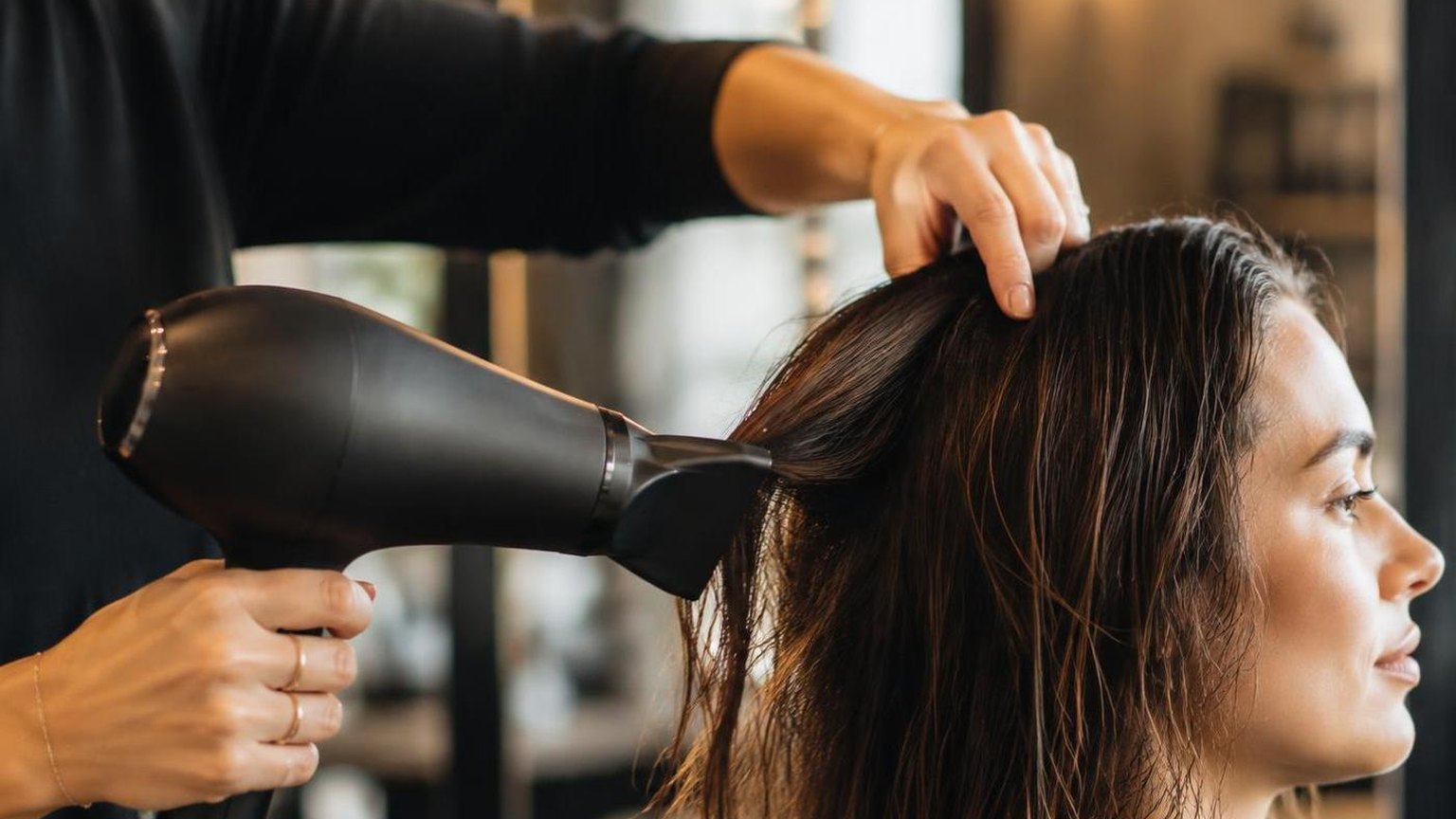 Brushes, clips and a professional dryer laid out on a clean counter, in a working salon