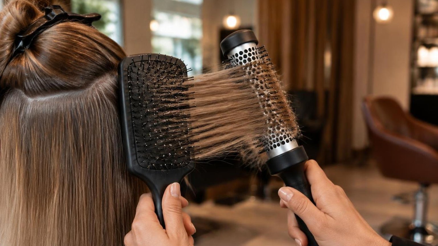 Hands checking tension on a round brush mid-section, close-up, in natural daylight